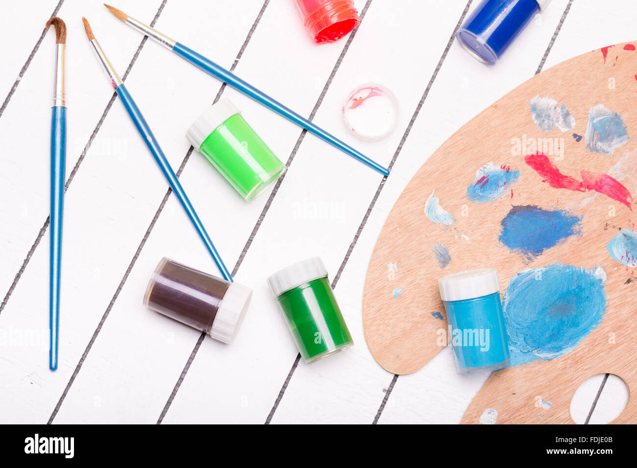 Watercolor and tempera with different paint brushes on a white wooden