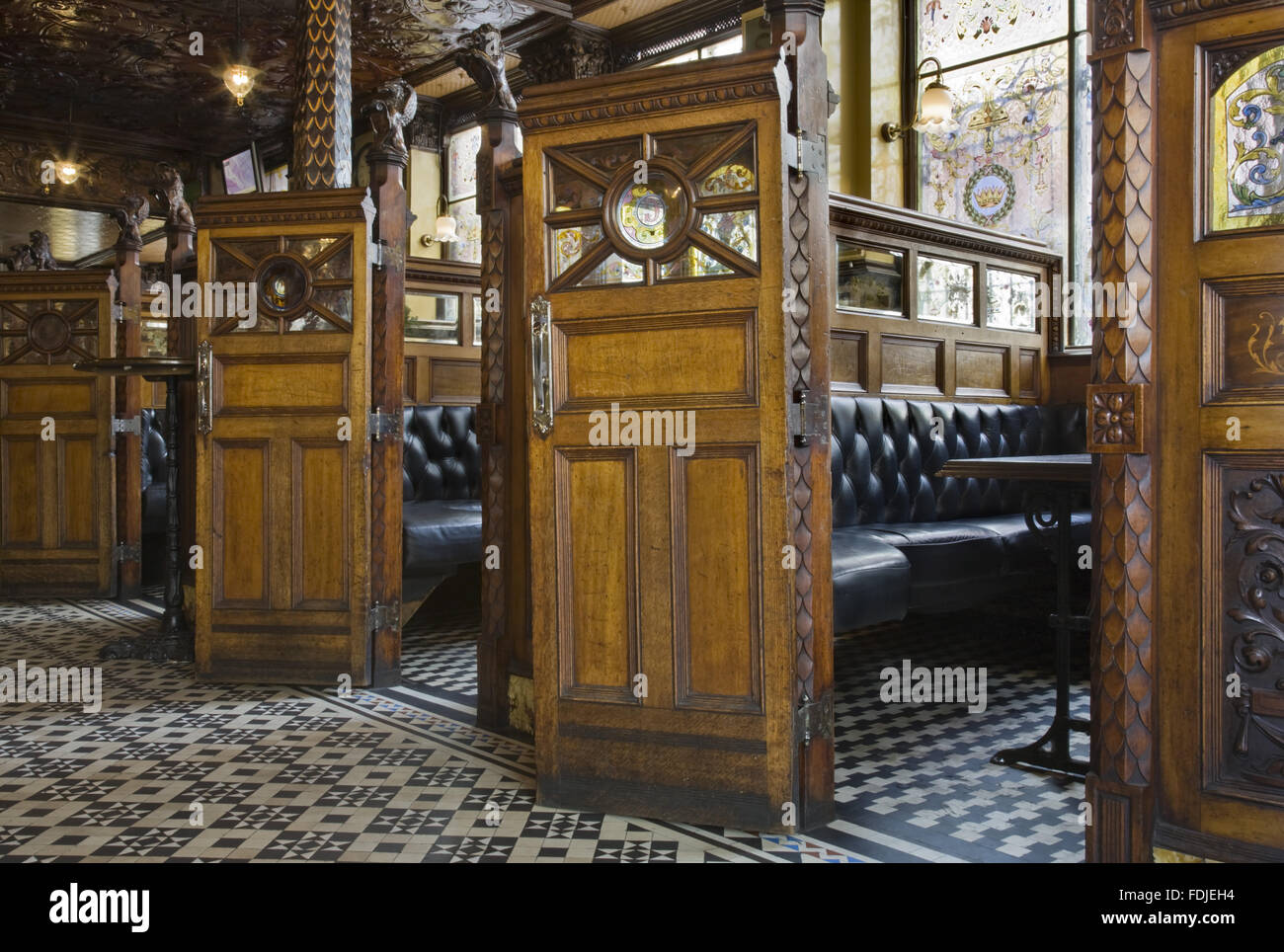 Wooden snugs along one wall of The Crown Bar, Great Victoria Street, Belfast. Formerly known as the Crown Liquor Saloon, the pub building dates from 1826 but the wonderful late Victorian craftsmanship of the tiling, glass and woodwork undertaken by Italia Stock Photo
