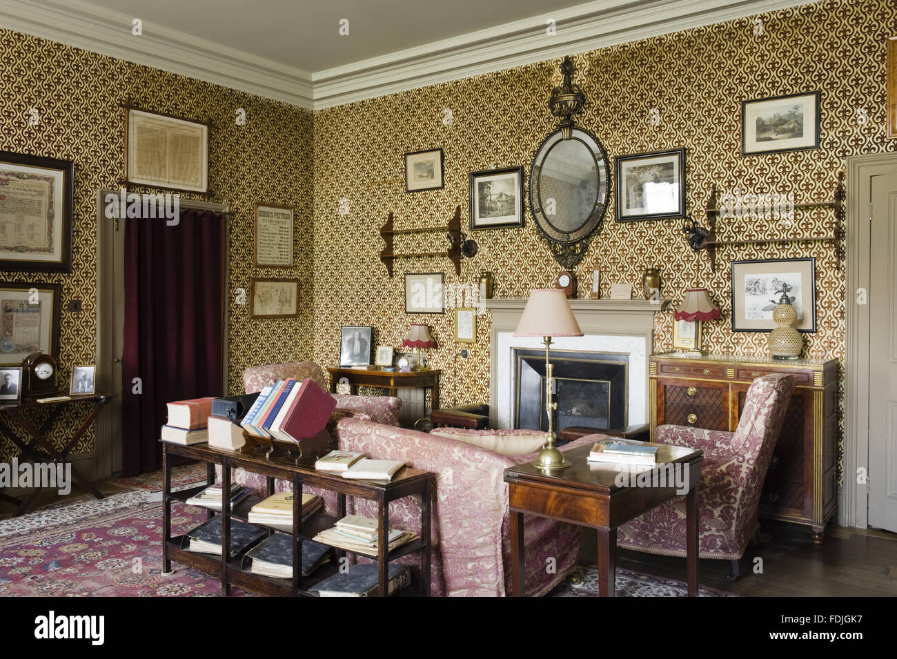 The Audit Room at Kingston Lacy, Dorset, with a view towards the fireplace, sofa and armchairs. Stock Photo