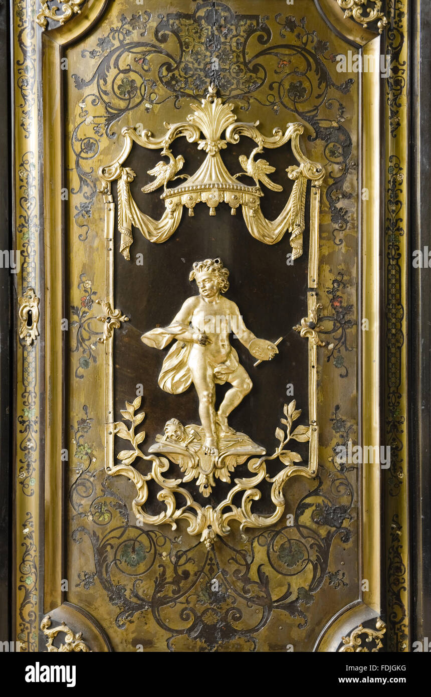 Close view of an eighteenth century ormolu plaque in the door of a nineteenth century contre-partie Boulle meuble d'entre deux, in the Saloon at Kingston Lacy, Dorset. Stock Photo