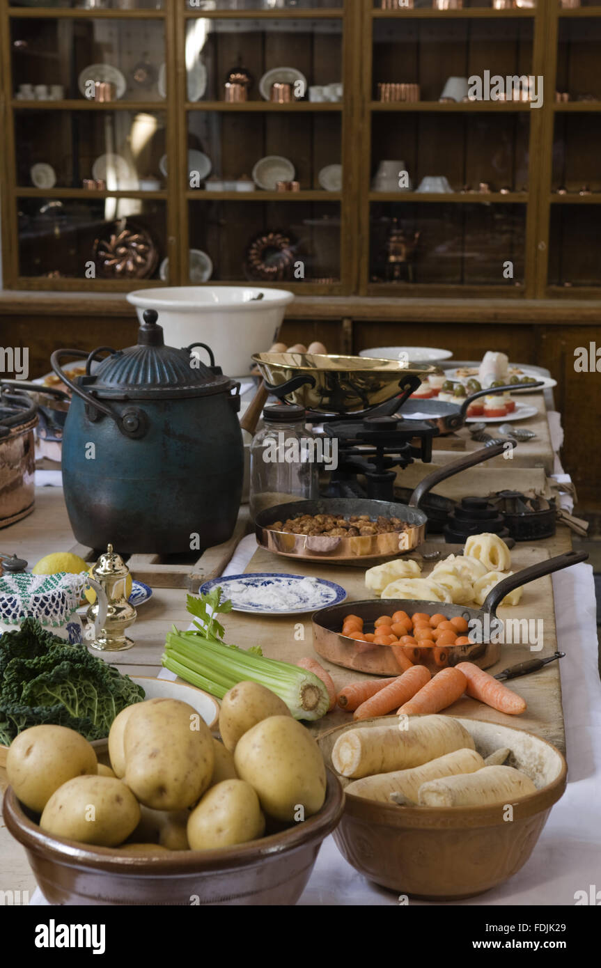 Close view of the table and food being prepared in the Kitchen at Lanhydrock, Cornwall. The dresser in the background houses a collection of china and utensils. Stock Photo