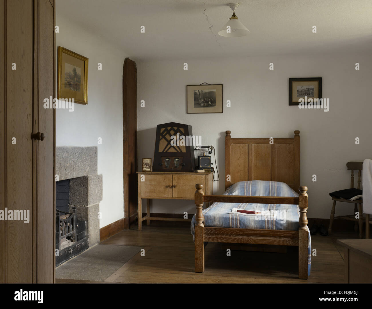 The Manservant's Room with a wooden bed and bedside cupboard, and a radio at Castle Drogo, Devon. Stock Photo