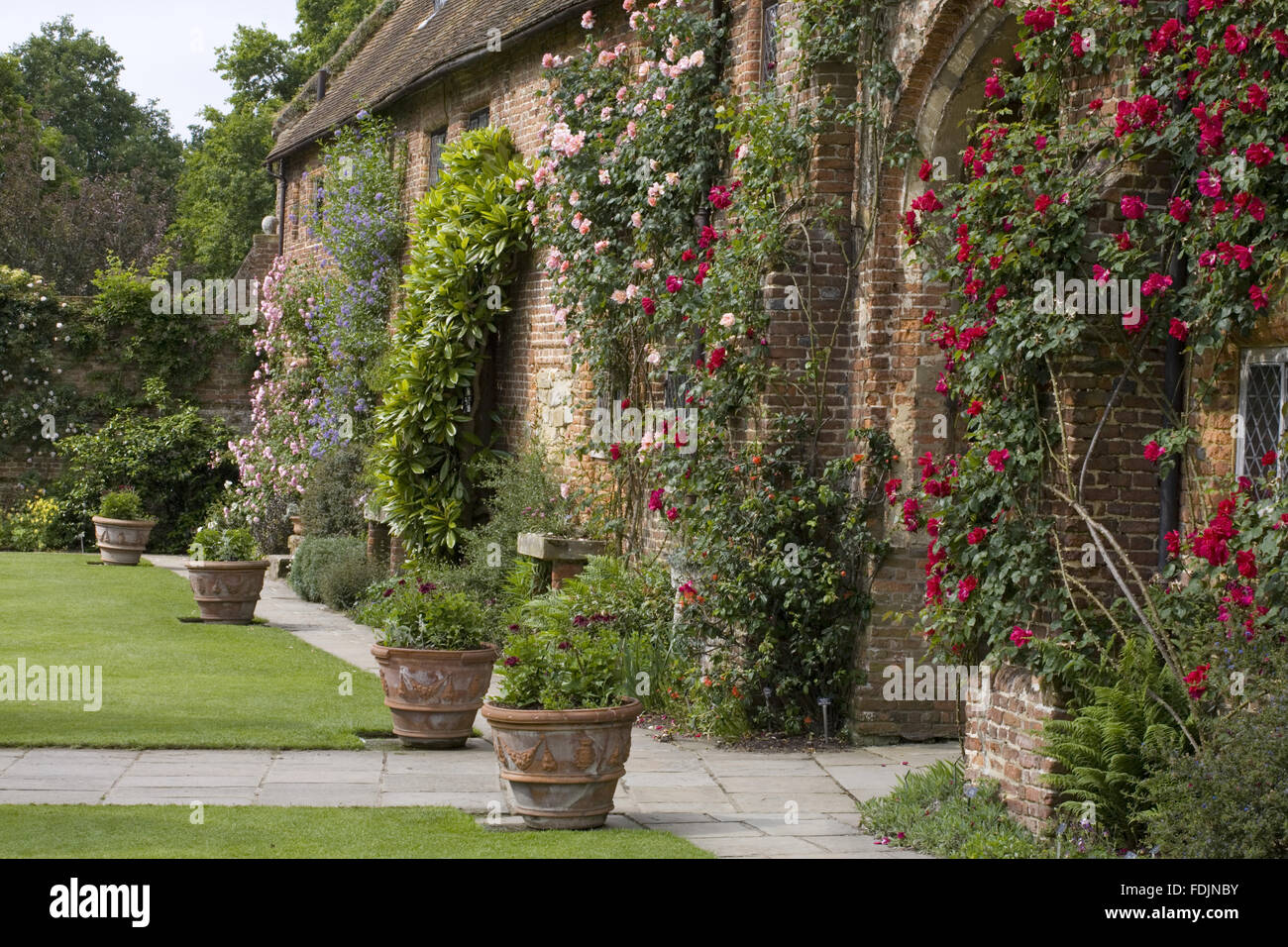 The front range and oldest part of the building, c.1490, seen here on the inner side of the Front Courtyard at Sissinghurst Castle Garden, near Cranbrook, Kent. The red rose 'Allen Chandler' climbs around the archway. Stock Photo