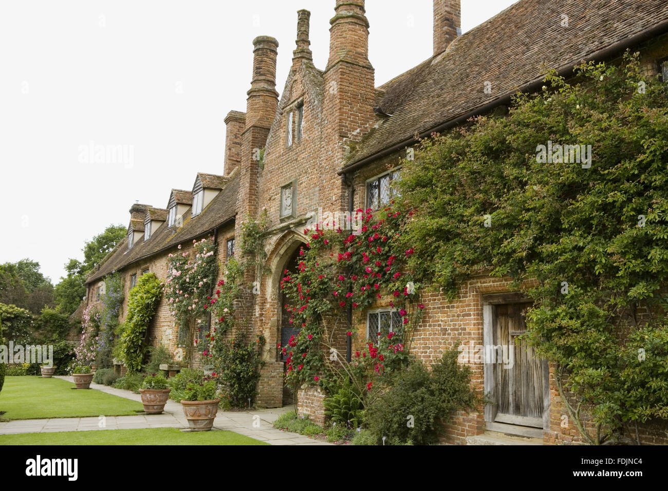 The front range and oldest part of the building, c.1490, seen here on the inner side of the Front Courtyard at Sissinghurst Castle Garden, near Cranbrook, Kent. The red rose 'Allen Chandler' climbs around the archway. Stock Photo
