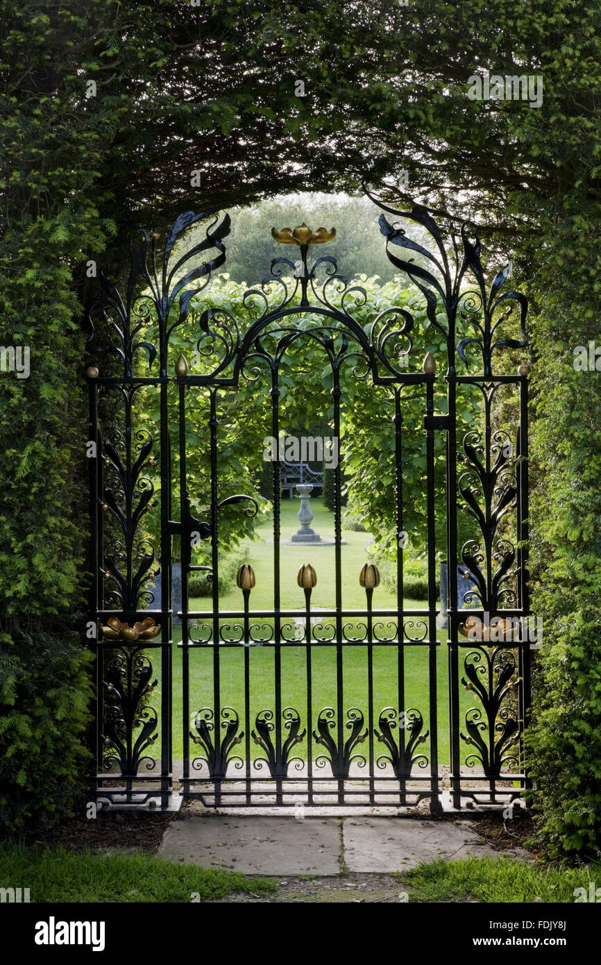 View through a decorative wrought-iron gate into the summer garden at Antony, Cornwall. Stock Photo