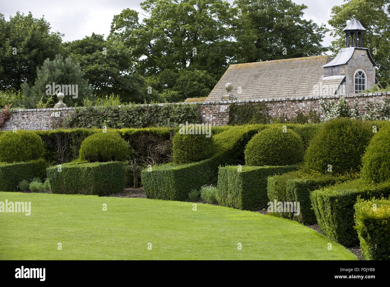The semi-circular lawn and topiary hedging in the garden at Avebury Manor, Wiltshire. Stock Photo