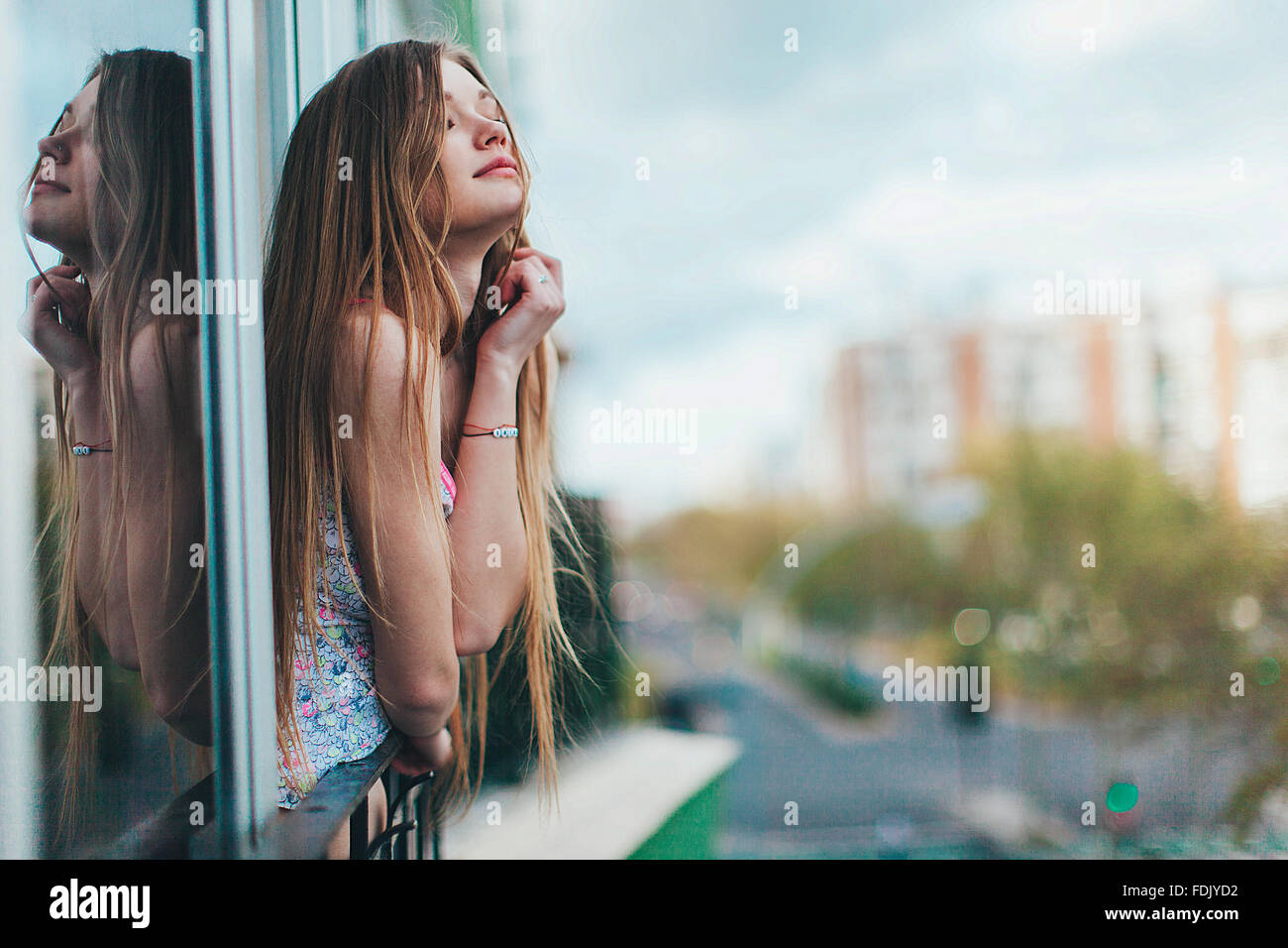 Young woman leaning out of a window in city, Seville, Spain Stock Photo