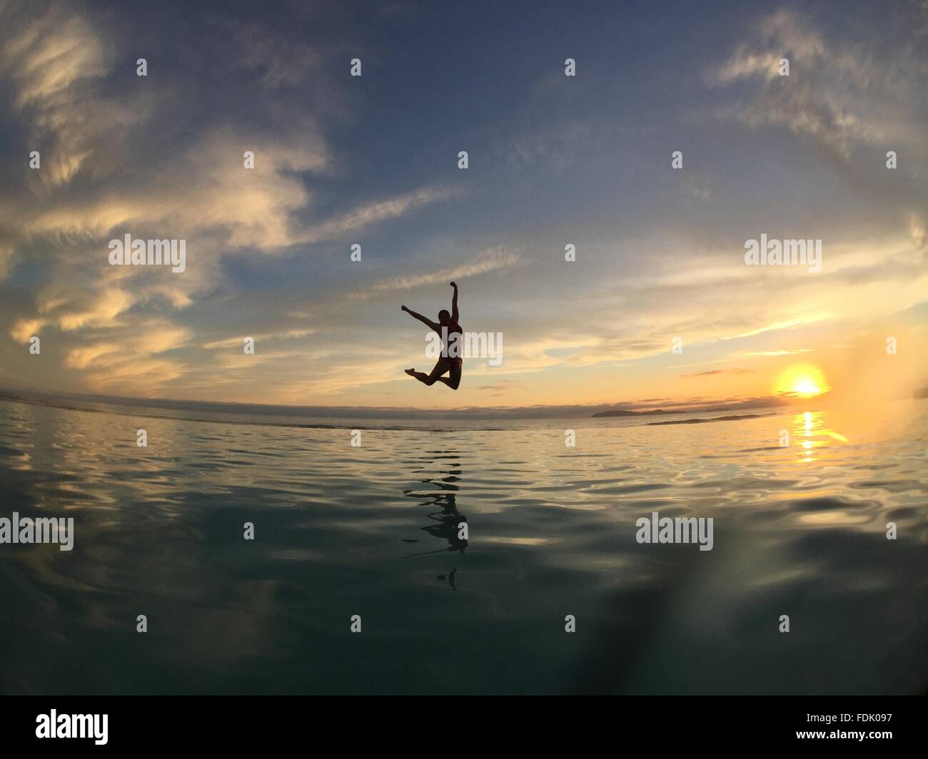 Silhouette of a Woman jumping in air over sea Stock Photo