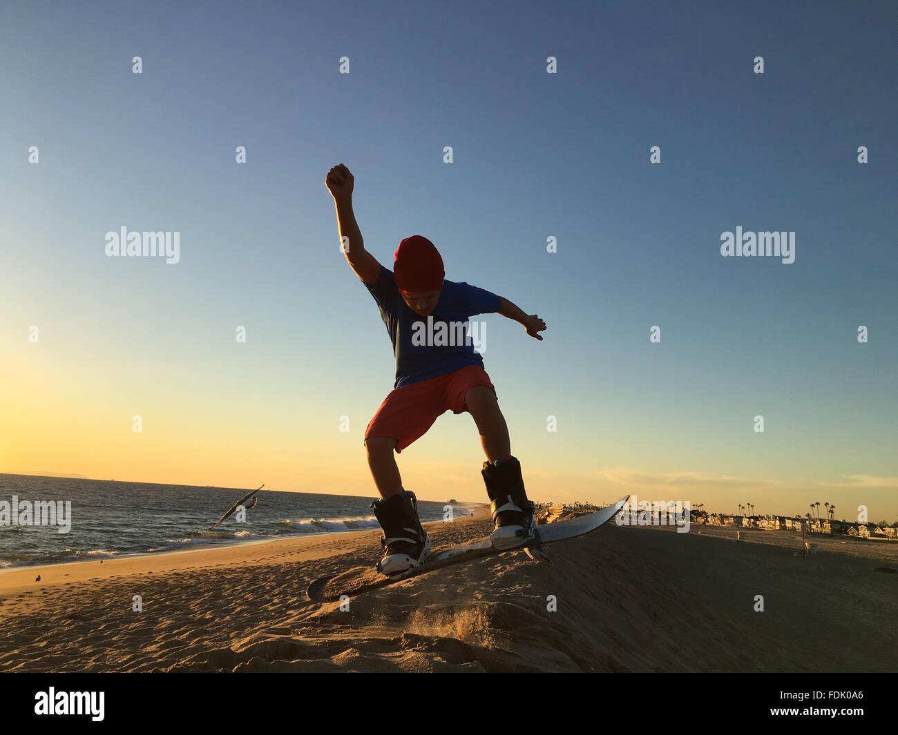 Boy sandboarding on beach Stock Photo