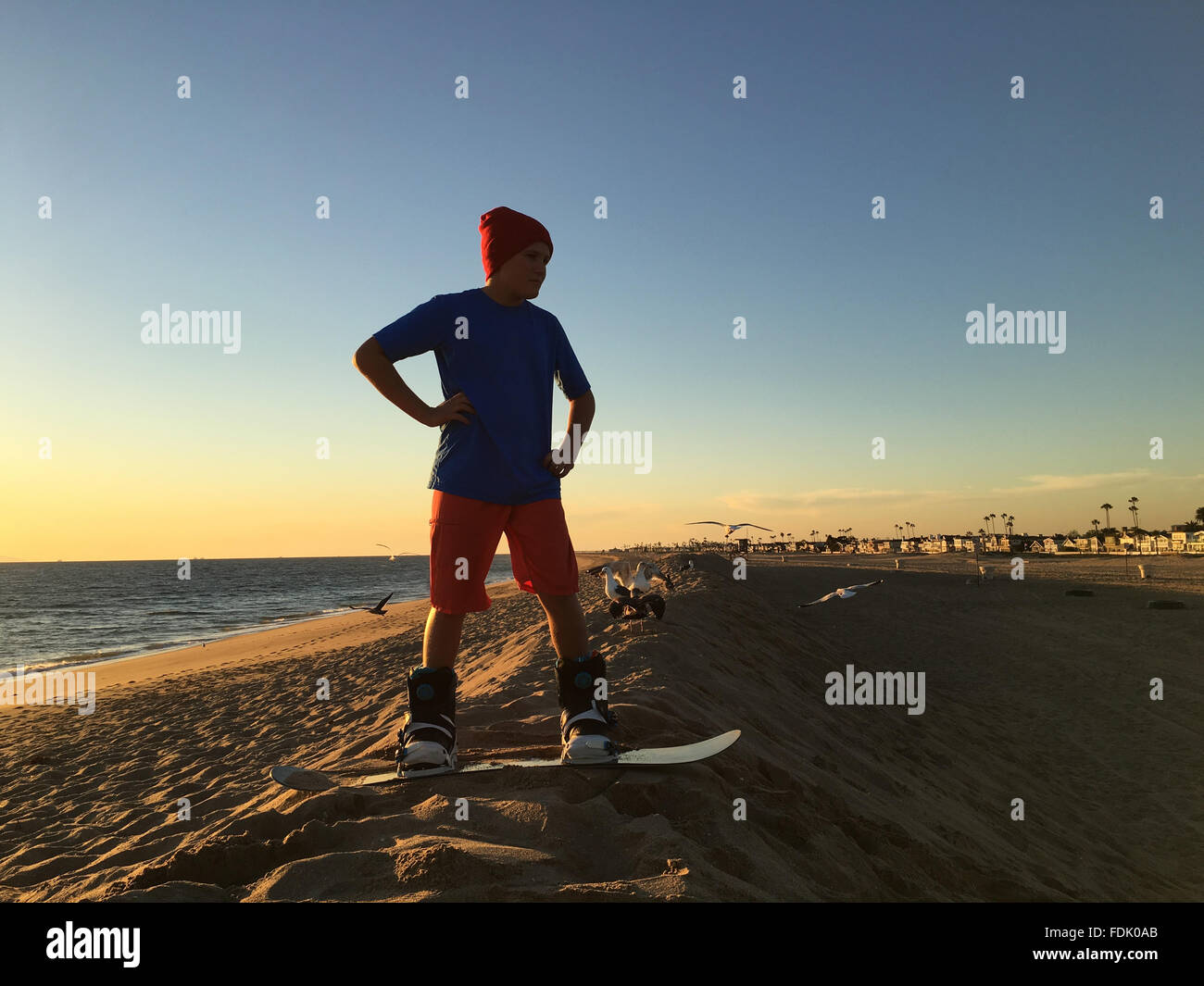 Boy standing on sandboard on the beach Stock Photo