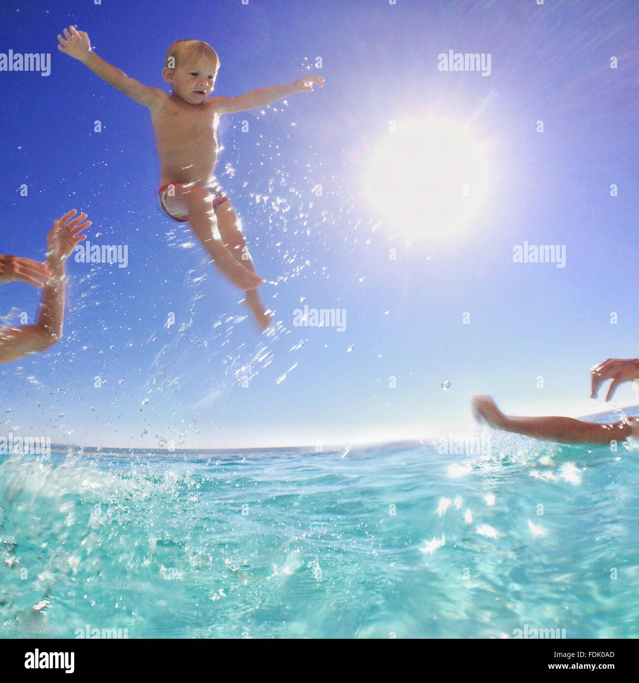 Father and son throwing baby brother in the air in the sea Stock Photo