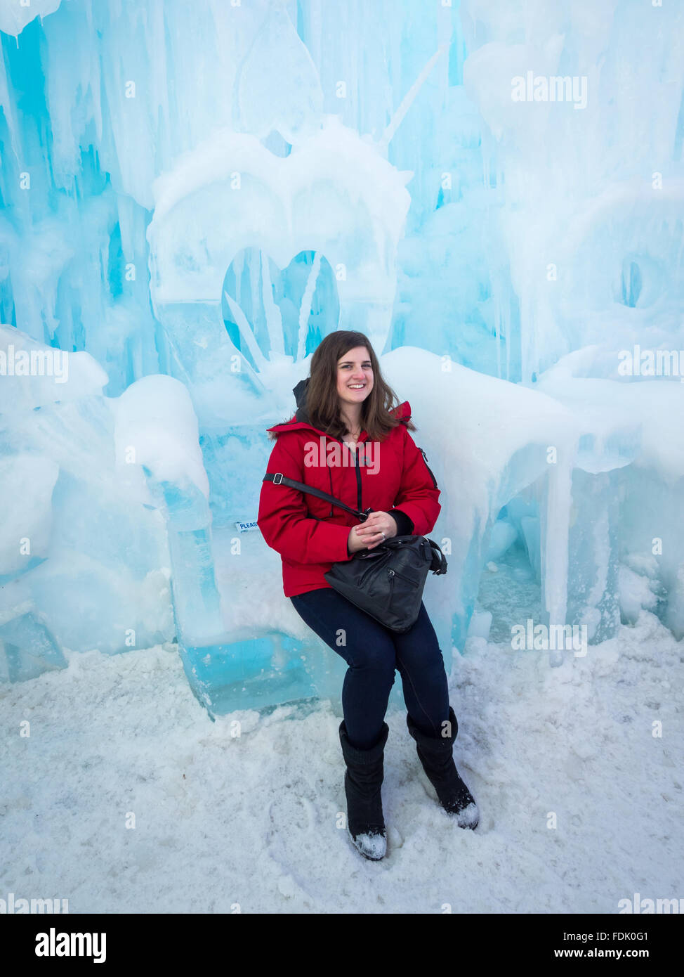 A pretty brunette girl sits on a throne sculpted from ice at the Ice Castle in Hawrelak Park, Edmonton, Alberta, Canada. Stock Photo