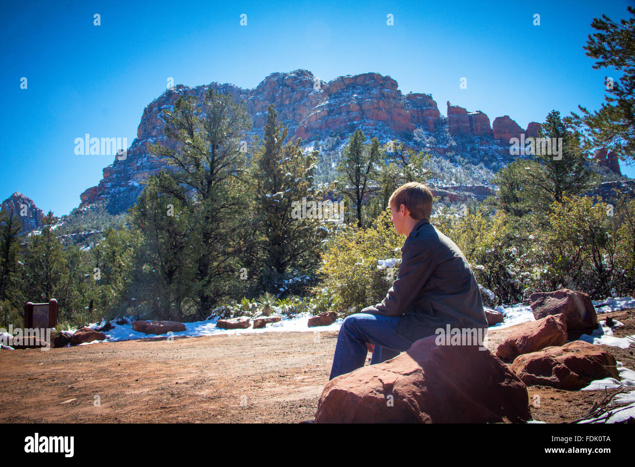 Boy sitting on rock looking at view, Sedona, Arizona, United States Stock Photo