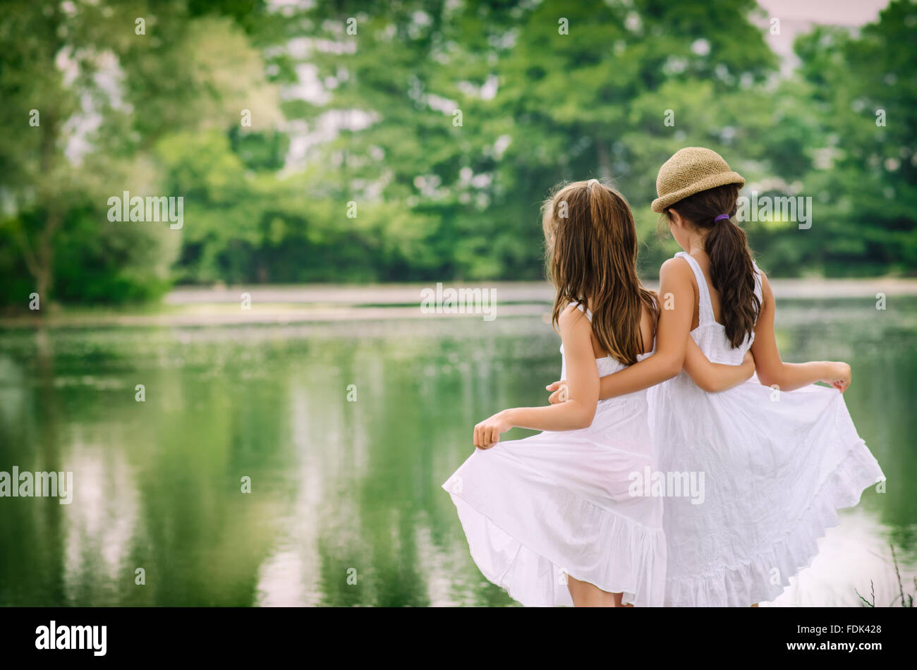 Rear view of two girls standing by a river embracing Stock Photo
