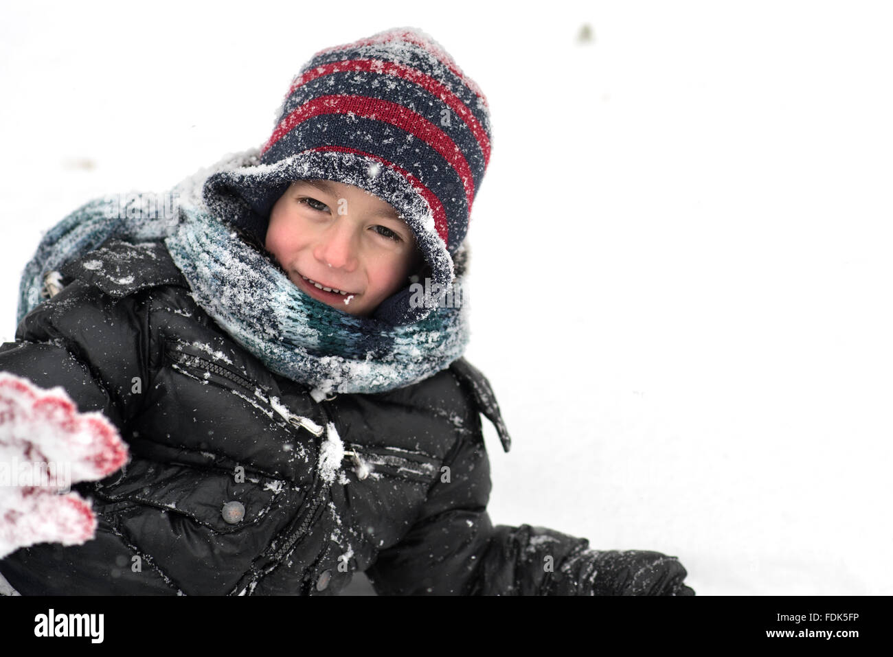 Smiling boy lying in the snow Stock Photo