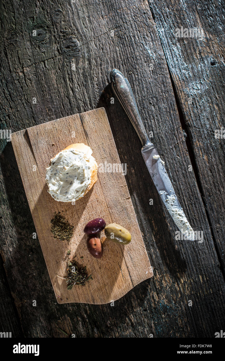 Bruschetta with soft cream cheese and olives on chopping board Stock Photo