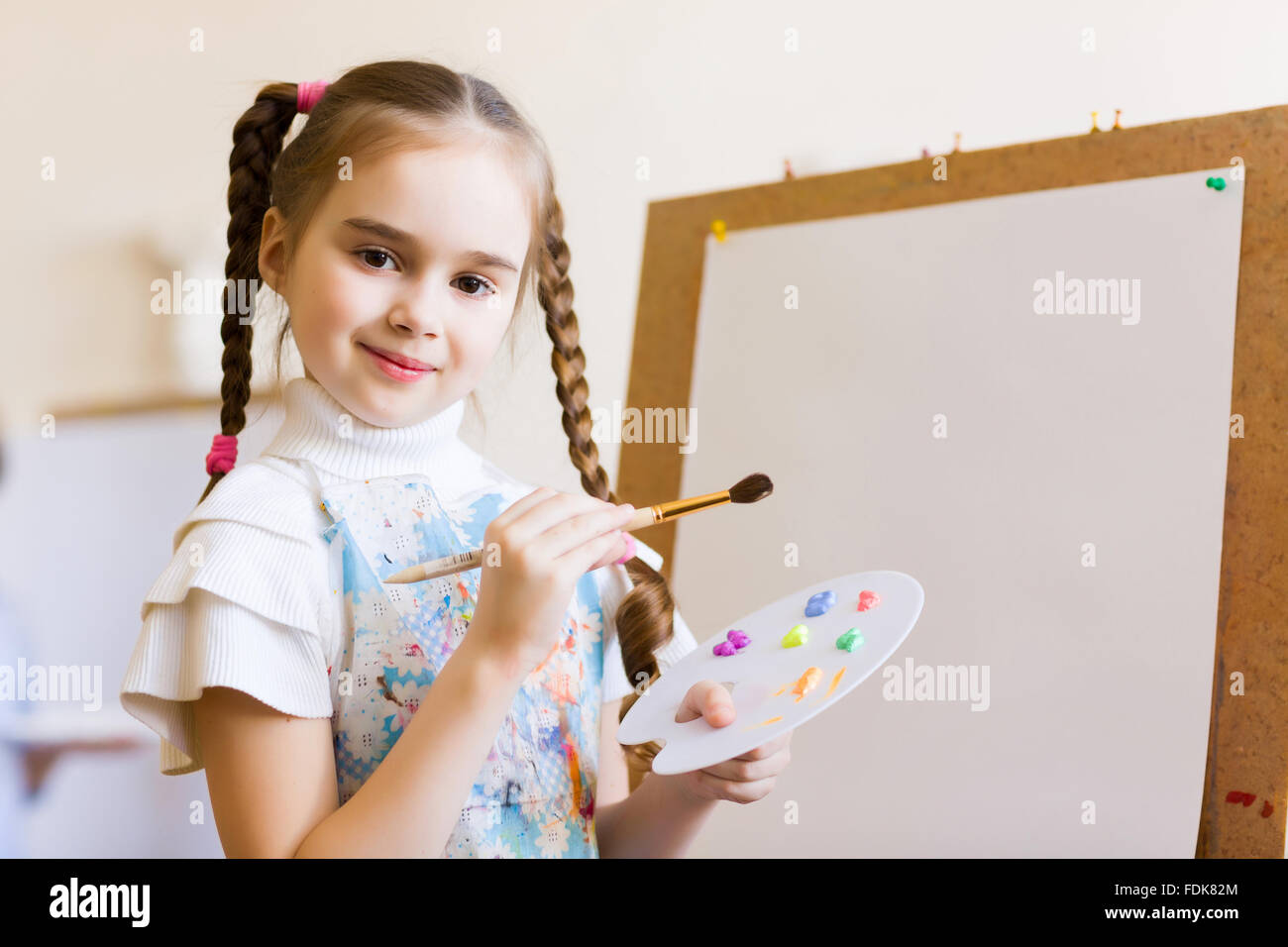 Little cute girl with paint brush and easel Stock Photo - Alamy