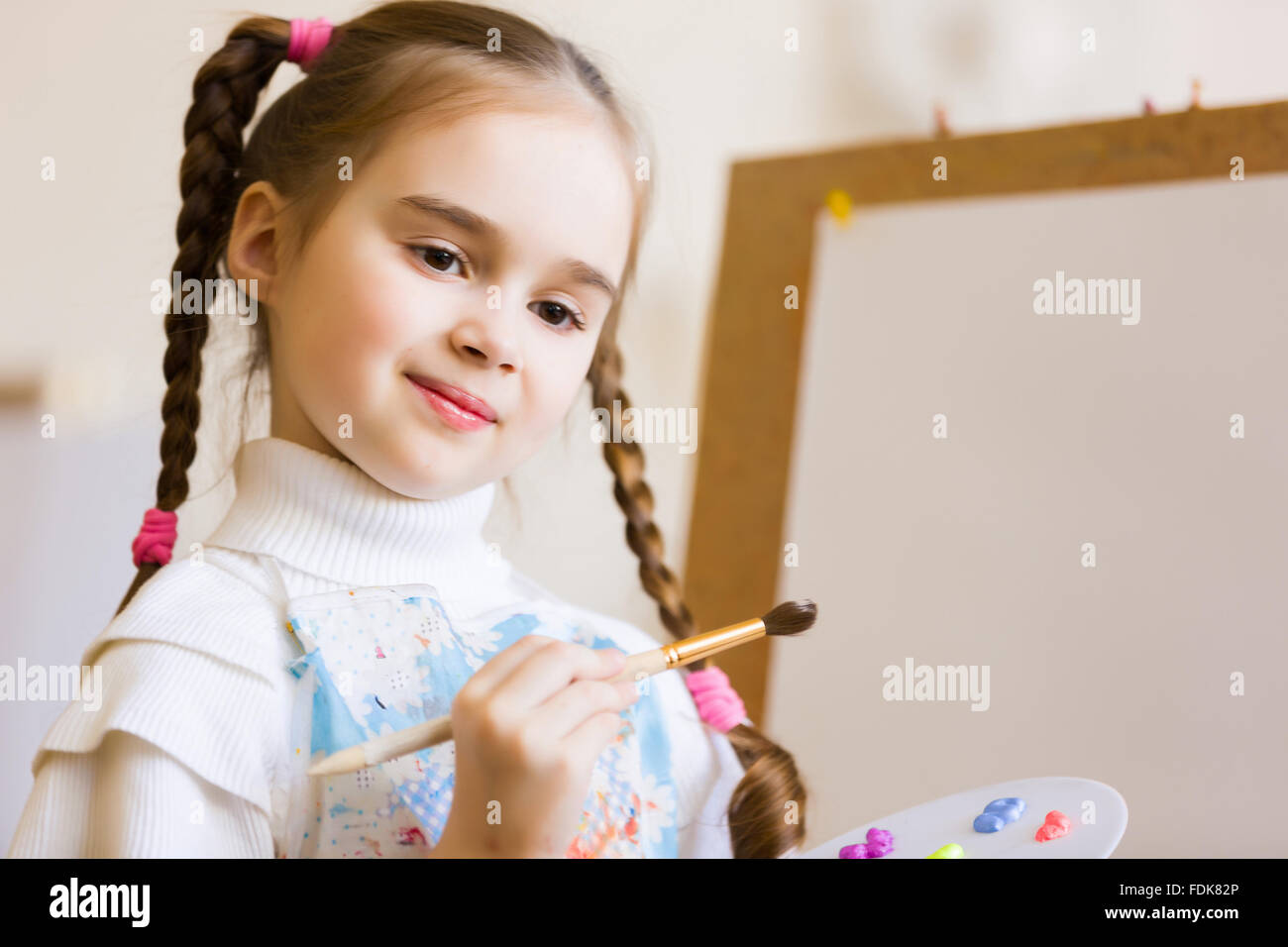 Little cute girl with paint brush and easel Stock Photo - Alamy