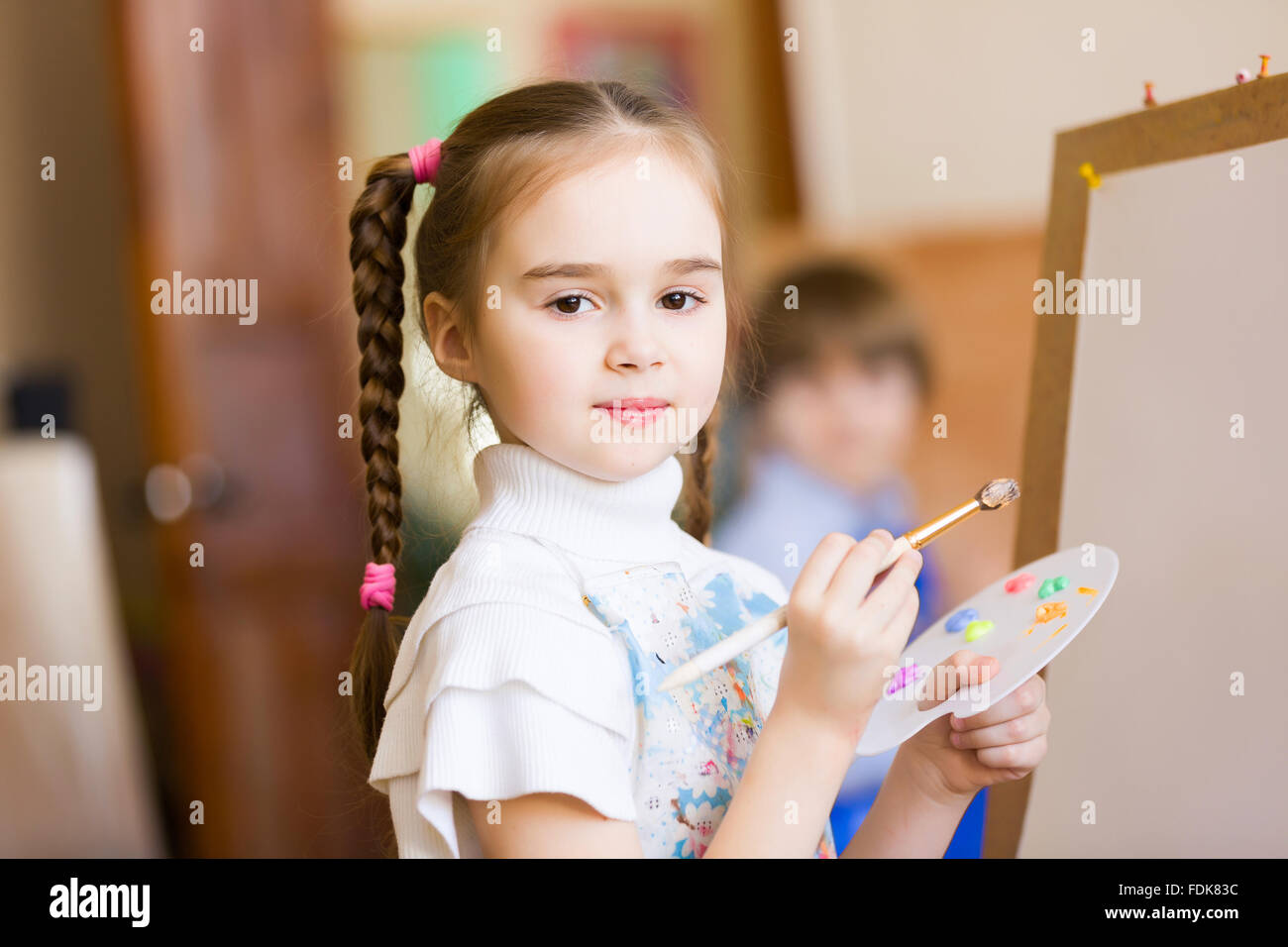 Little cute girl with paint brush and easel Stock Photo - Alamy