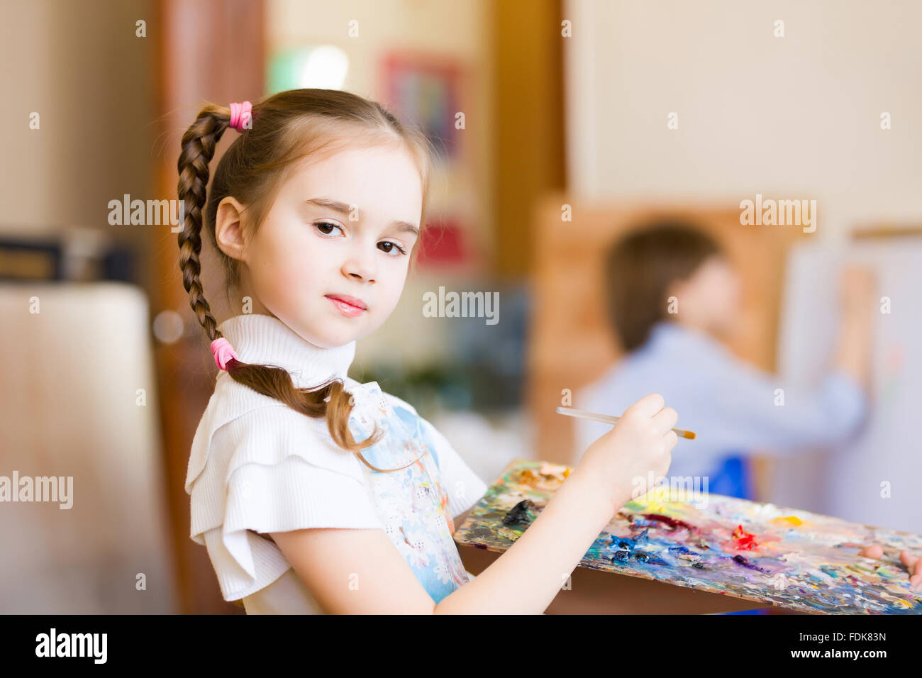 Little cute girl with paint brush and easel Stock Photo - Alamy