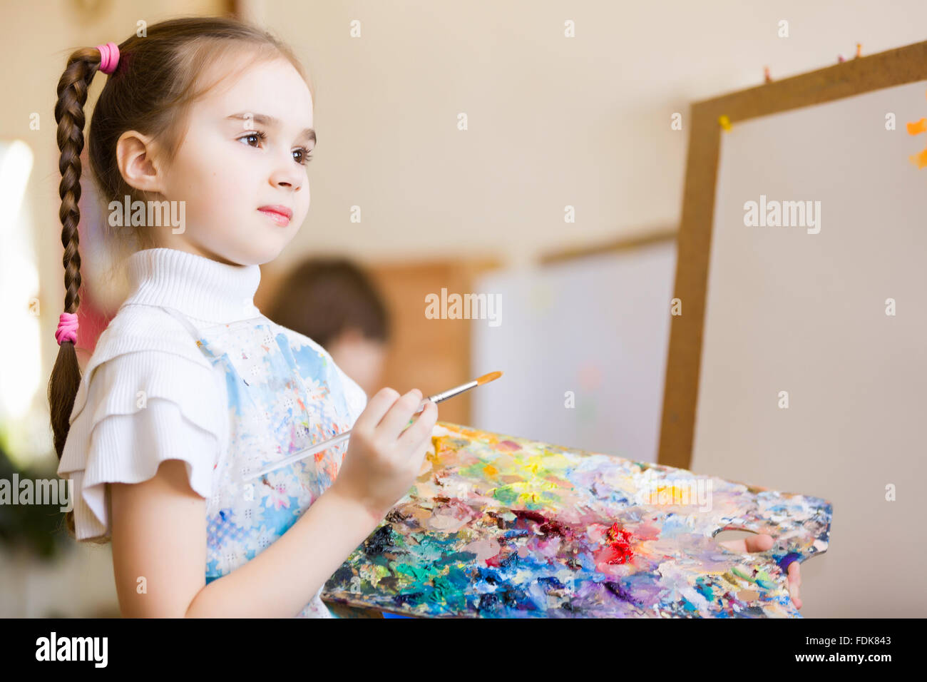 Little cute girl with paint brush and easel Stock Photo - Alamy