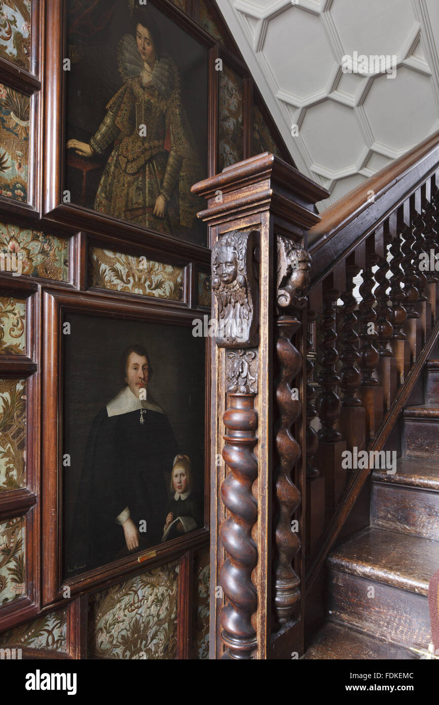 Newel post on the stairs and paintings on the leather hangings on the wall of the North Staircase at Oxburgh Hall, Norfolk. Stock Photo