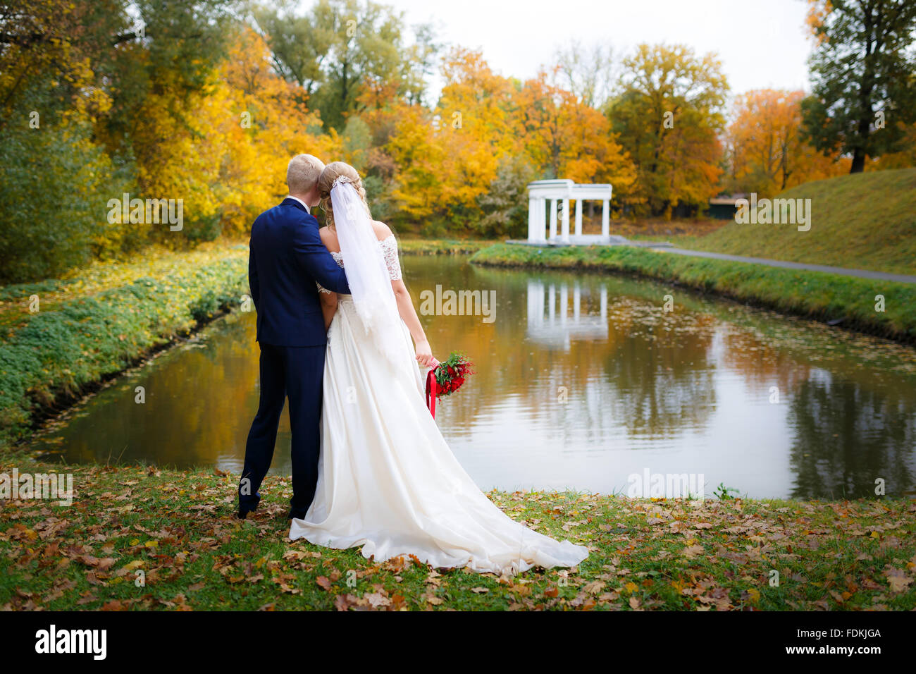 Wedding couple hugging by the lake in the fall Stock Photo