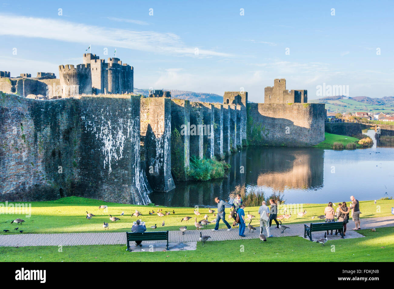 People walking around outside Caerphilly castle a Medieval castle with moat in Caerphilly South Glamorgan South Wales GB UK Europe Stock Photo