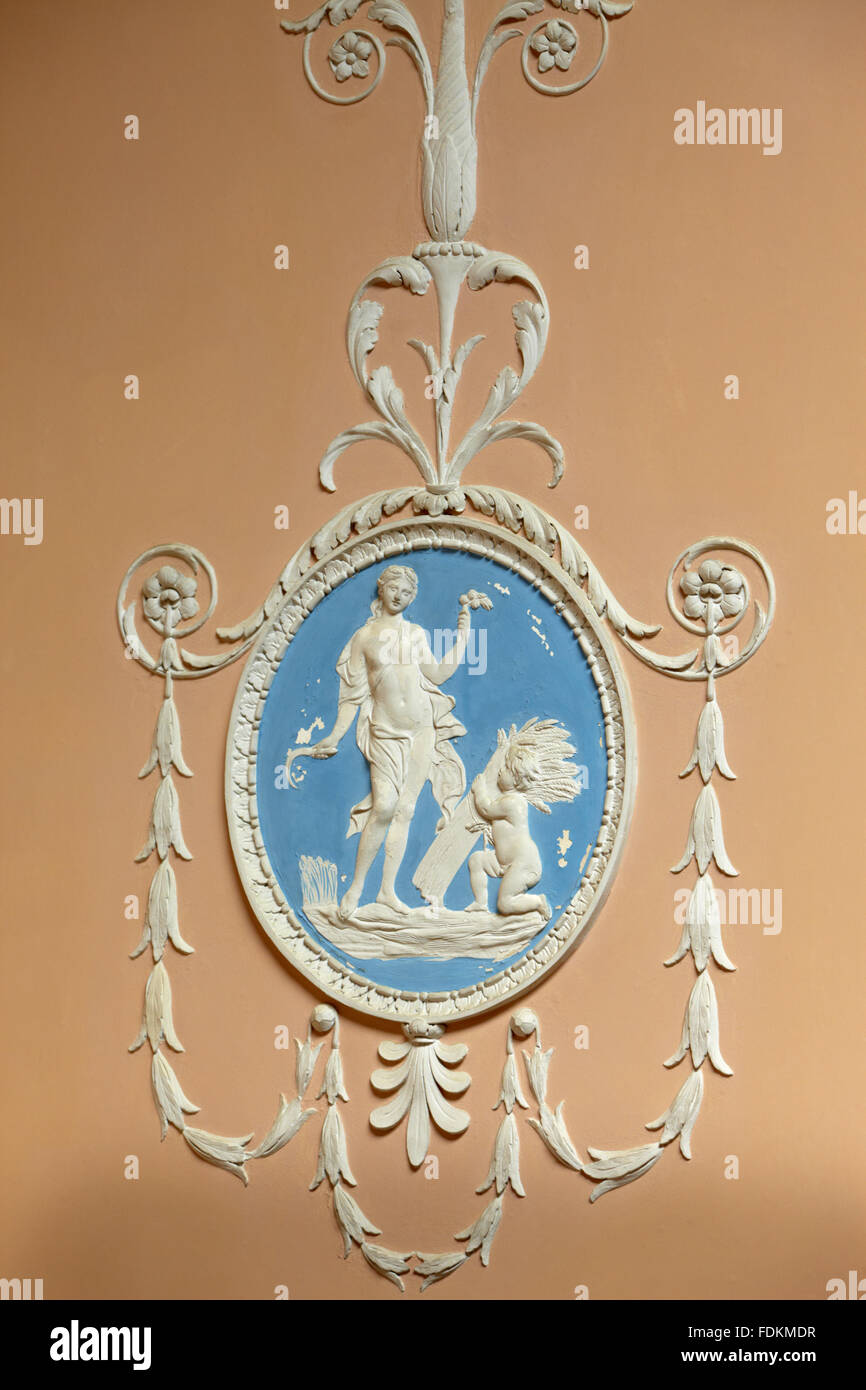 Relief plasterwork in white on Wedgewood blue background on the pink wall of the Staircase at Claydon, Buckinghamshire. Stock Photo