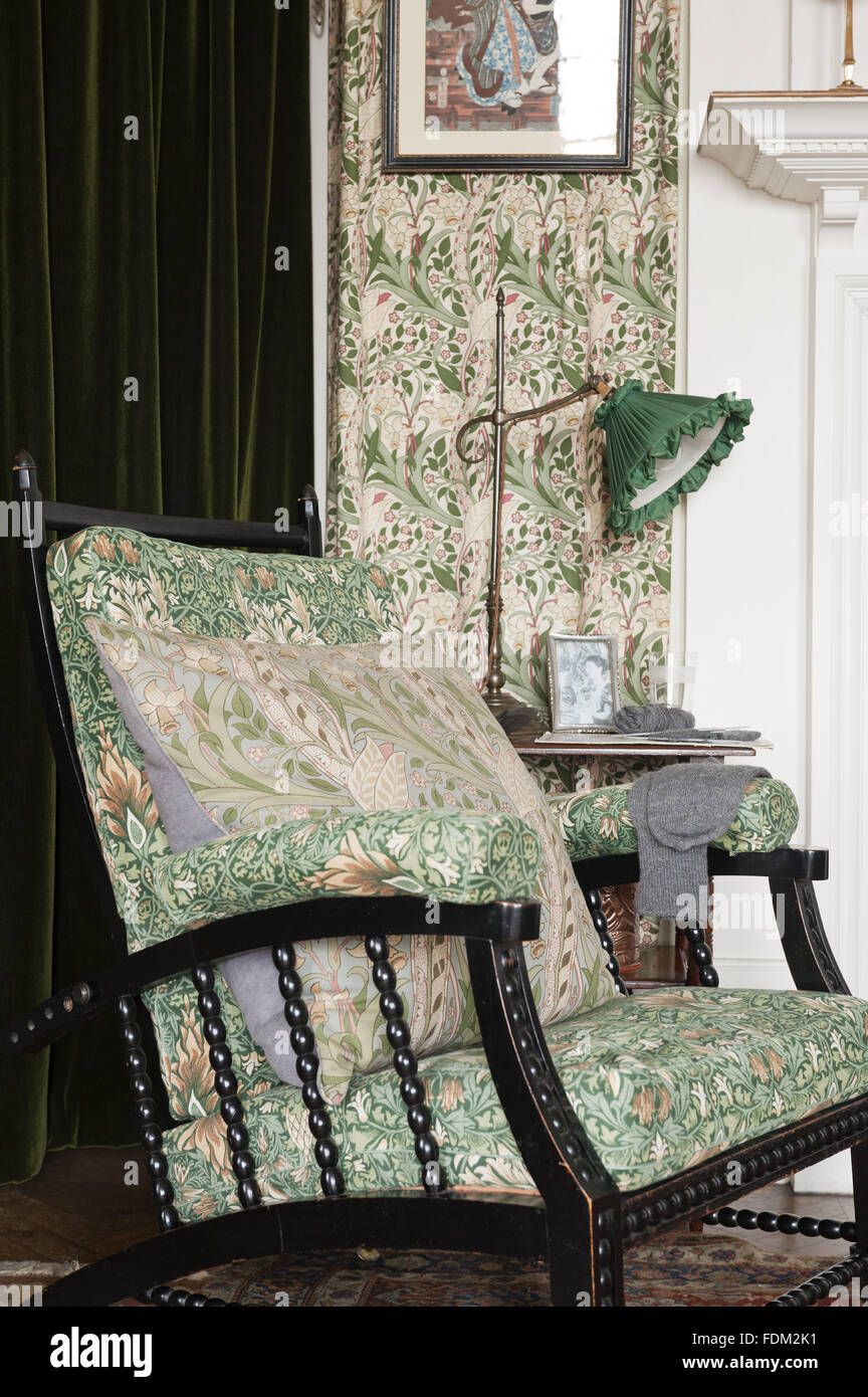 Morris and Co adjustable chair, upholstered in William Morris 'Snakeshead' chintz, in the Morning Room at Standen, West Sussex. Stock Photo