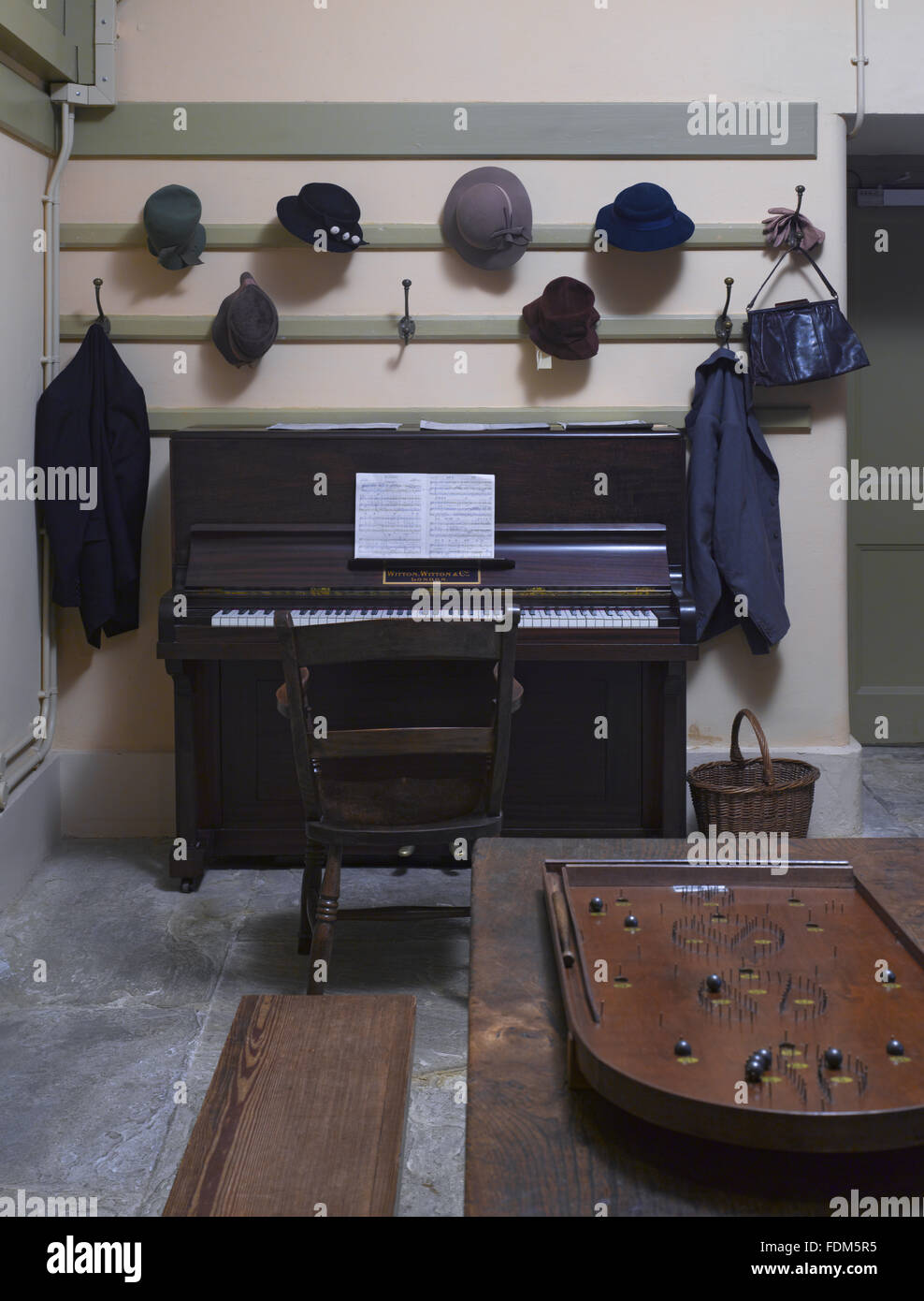 Hats and coats hung above a piano in the Servants' Hall in the Basement at Ickworth, Suffolk. Stock Photo