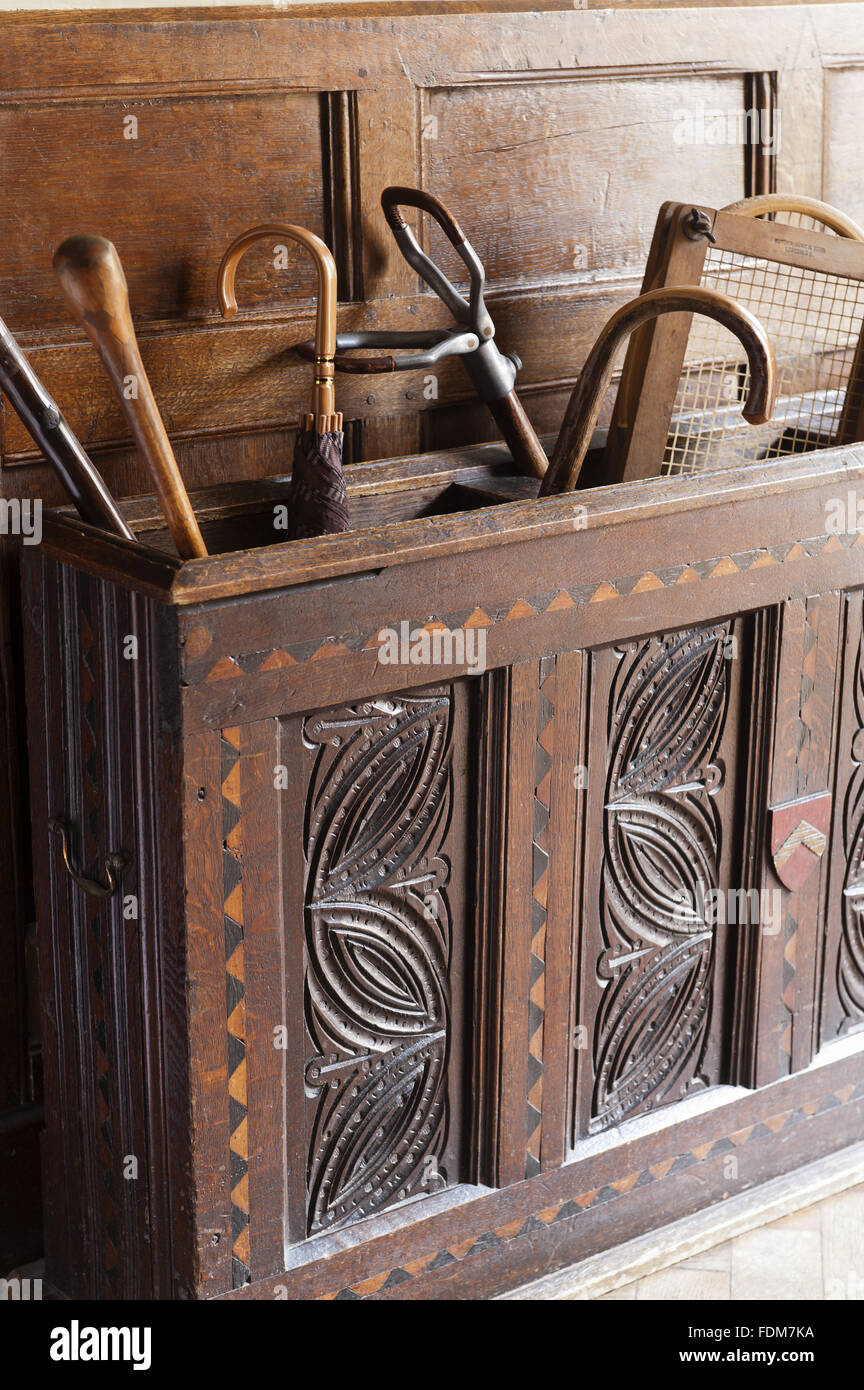 Carved wooden chest with umbrellas, walking sticks and a tennis raquet in the Garden Hall at Coughton Court, Warwickshire. Stock Photo