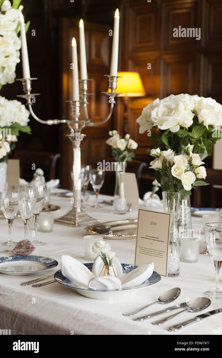 The Dining Room Table Laid With Candles And Seasonal Flowers At
