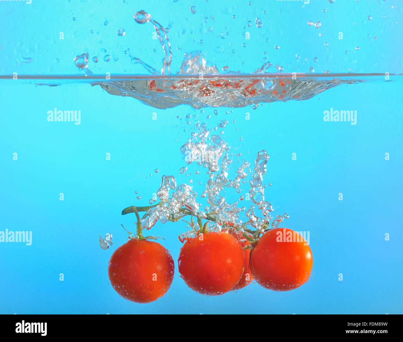 red tomatoes dropped into water isolated Stock Photo