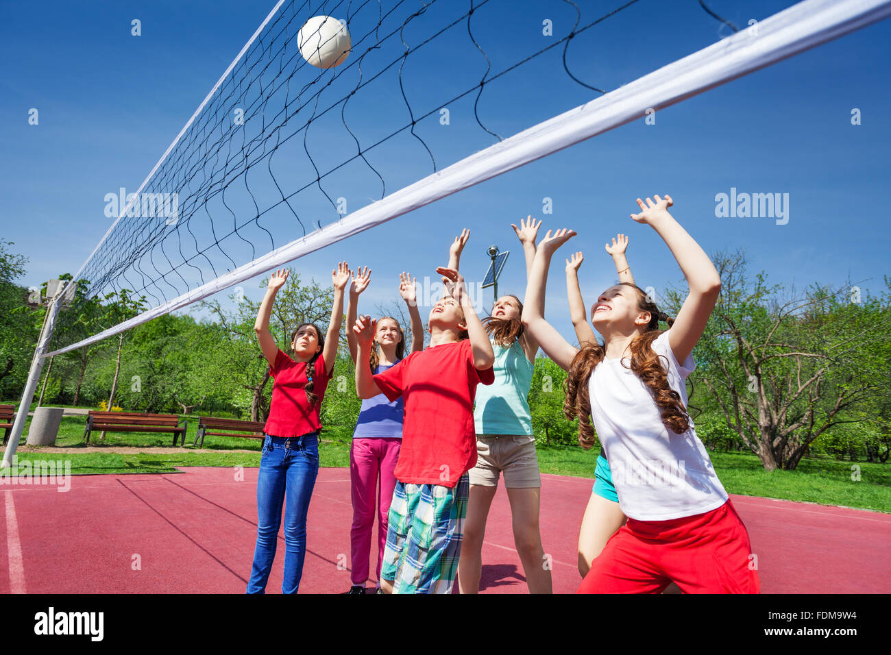 Group of teens with arms up play volleyball Stock Photo Alamy