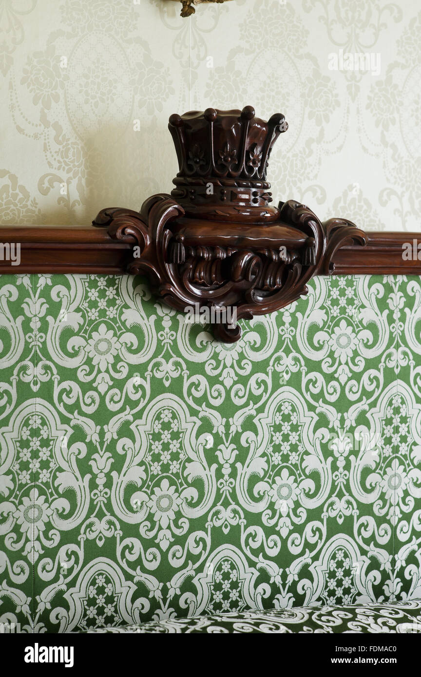 Detail of the bedstead decoration in the Green Silk Room at Dunham Massey, Cheshire. The bedstead is Victorian mahogany with moulded borders. NT inventory number 931194. Stock Photo