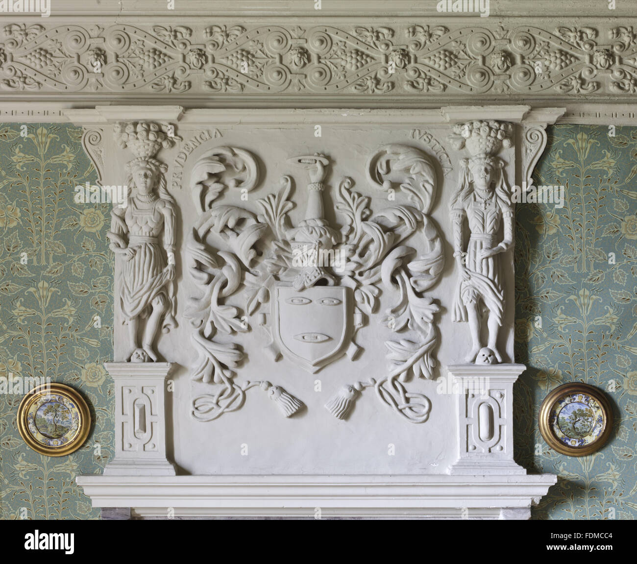 Plasterwork overmantel in the Huntroyde Room at Gawthorpe Hall, Lancashire. The overmantel dates from 1604, by Francis and Thomas Gunby, and features the arms, helm, crest and motto of the Shuttleworths, supported by two female figures representing the vi Stock Photo