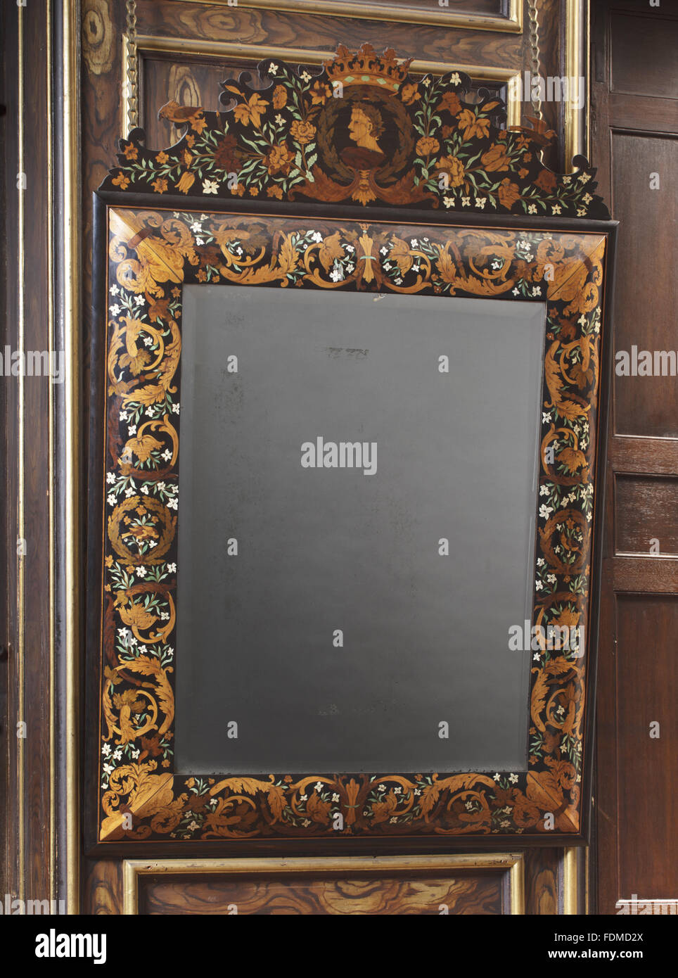 Wall mirror, 1675, of ebony, decorated with floral marquetry in various woods and ivory, some of which is stained green, at Ham House, Surrey. It has a convex frame decorated with floral marquetry of scrolling acanthus leaves. The elaborately shaped crest Stock Photo