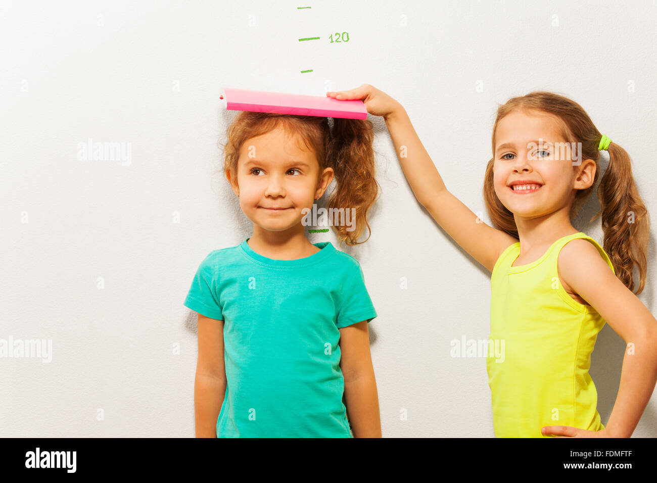 Girls measure height on wall scale Stock Photo