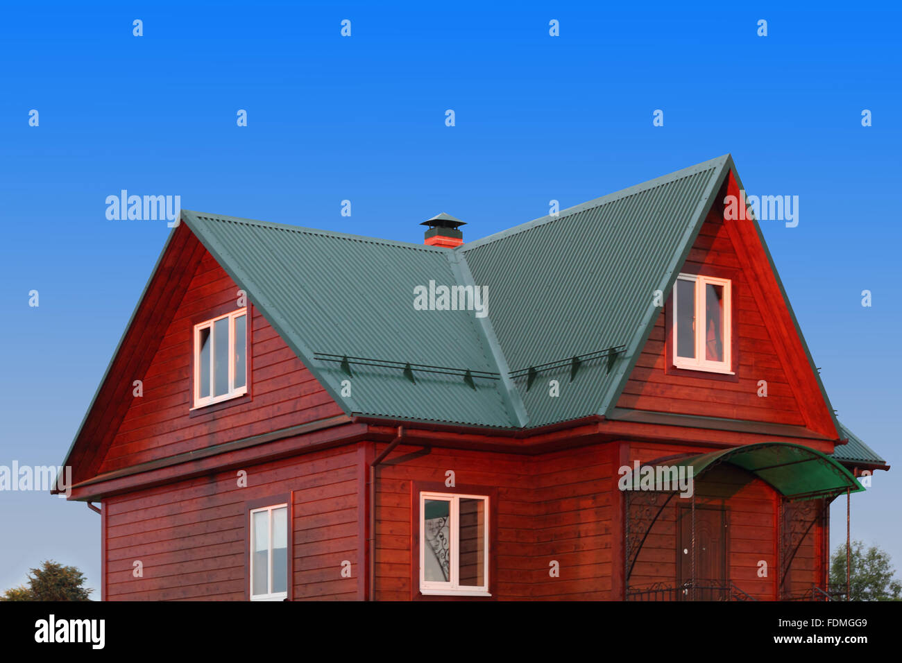 Wooden house under green metal roof with white plastic windows photo Stock Photo