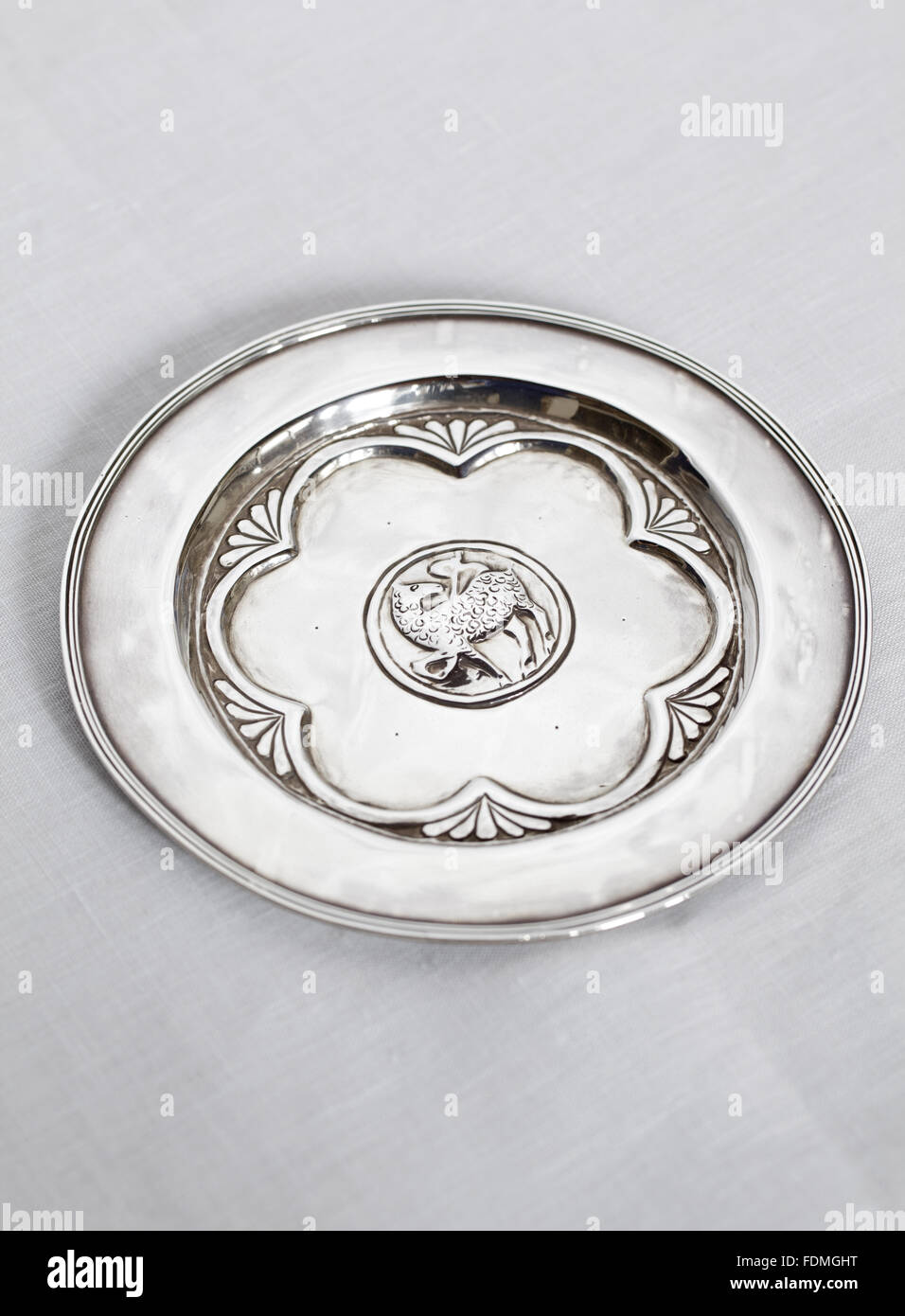 A small silver alms plate/paten with a lamb embossed in the centre by W. Herbert Durst. Commisioned in 1929 by John Louis Behrend (1881-1972) and (Phyllis) Mary Sandham, Mrs Behrend (1884-1977). Stock Photo