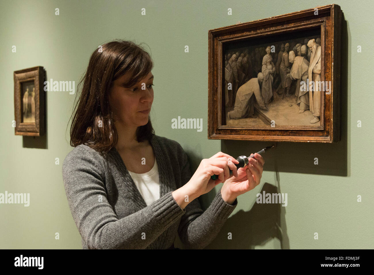 London, UK. 1 February 2016. A Courtauld Gallery employee holds the Bruegel painting Christ and the Woman Taken in Adultery, 1565. Bruegel in Black and White: Three Grisailles Reunited at The Courtauld Gallery. From 4 February to 8 May 2016 Pieter Bruegel the Elder’s three surviving grisaille paintings will be shown together for the first time at The Courtauld Gallery. The three panels will be accompanied by comparative prints and contemporary replicas, alongside other independent grisailles to examine their legacy and the development of this genre in Northern Europe. Stock Photo