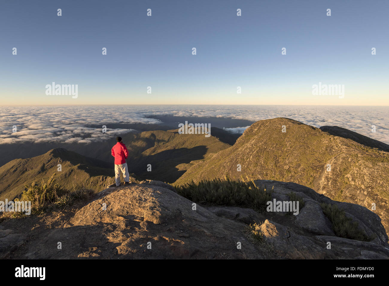 Turista no cume do Pico da Bandeira ao amanhecer - Parque Nacional do Caparaó Stock Photo
