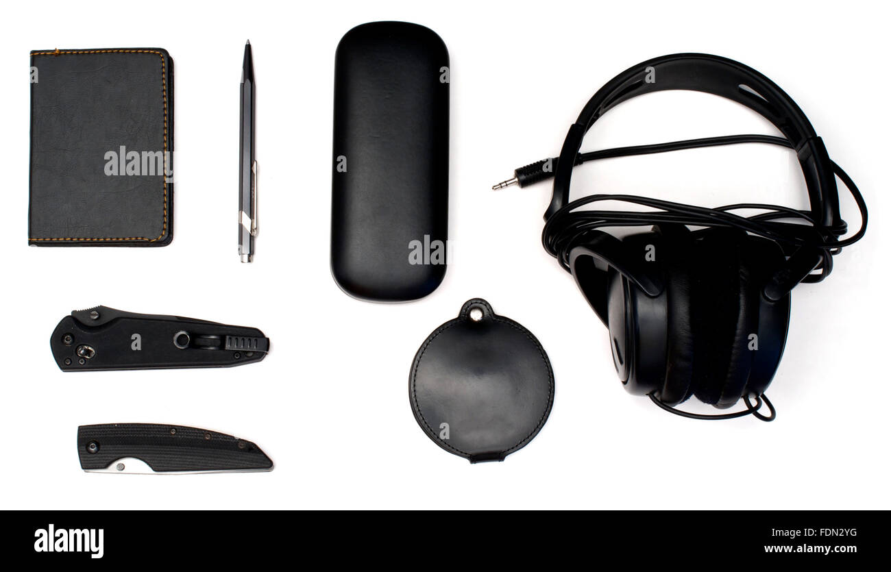Isolated knives, notebook, headphones, eyeglass case and pen over white