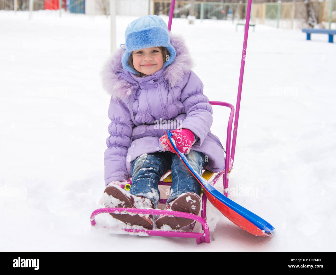 disheveled and happy five year old girl sitting on a sled Stock Photo ...