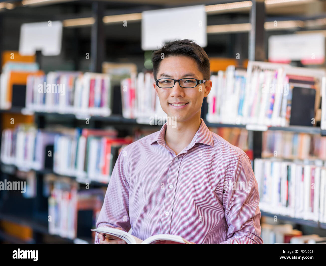 Happy male asian student holding books at the library Stock Photo - Alamy