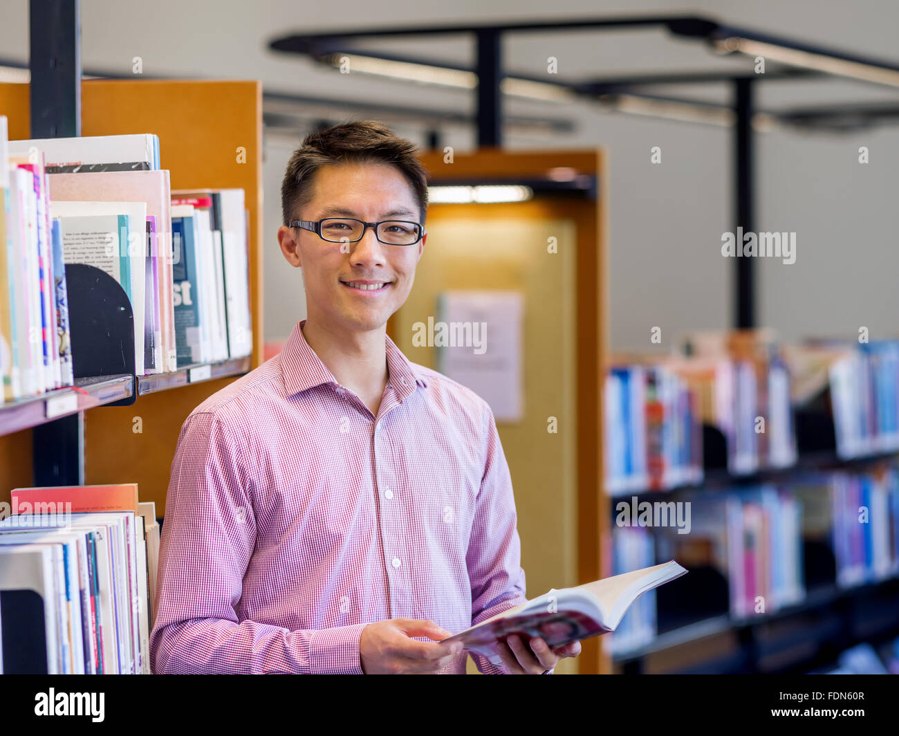 Happy male asian student holding books at the library Stock Photo - Alamy