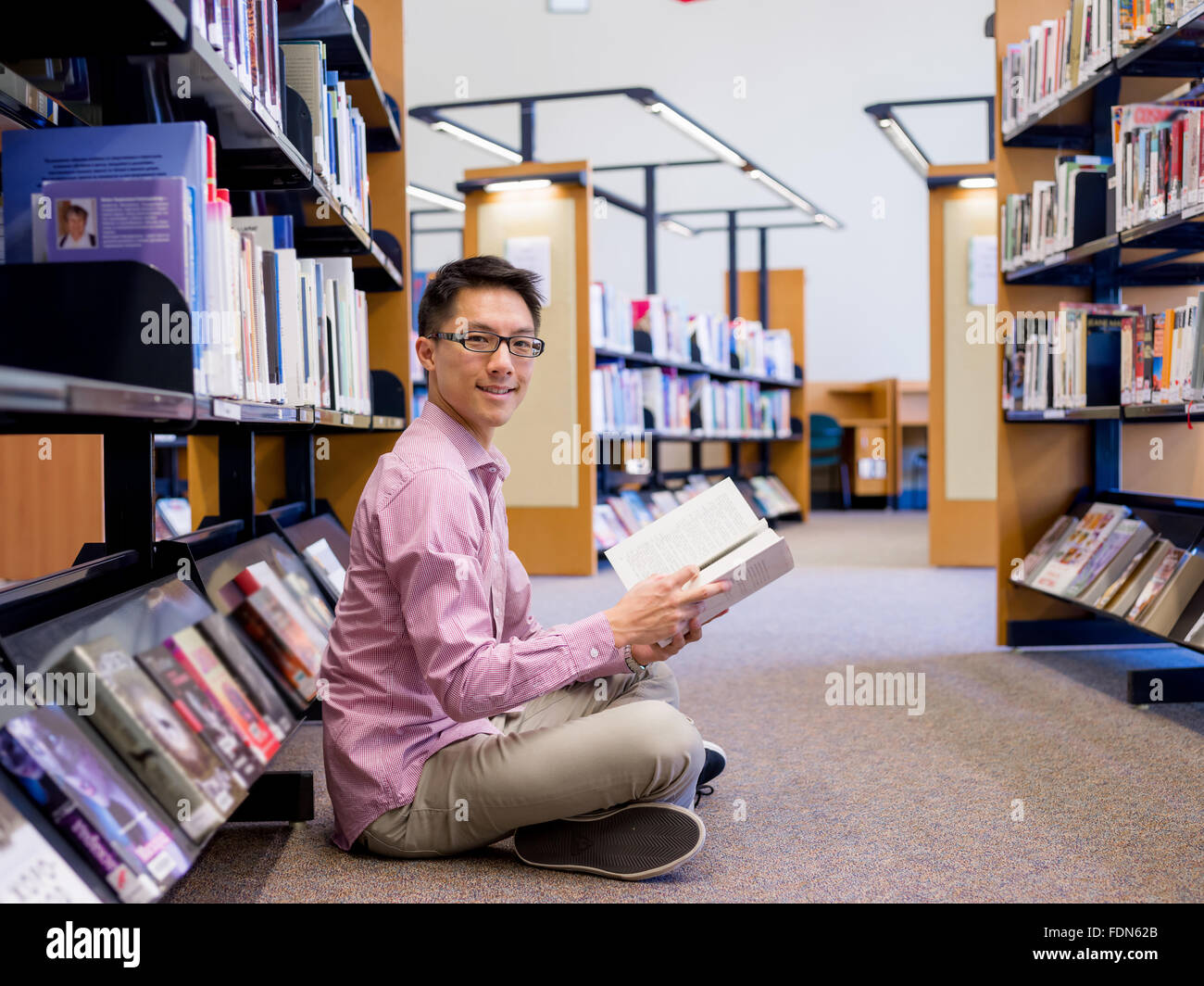 Happy male asian student holding books at the library Stock Photo - Alamy