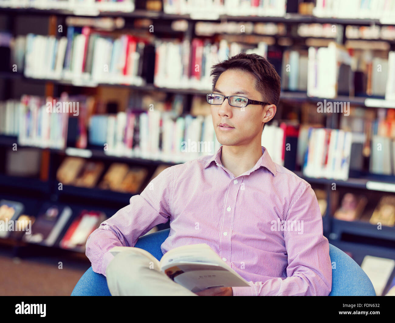 Happy male asian student holding books at the library Stock Photo - Alamy
