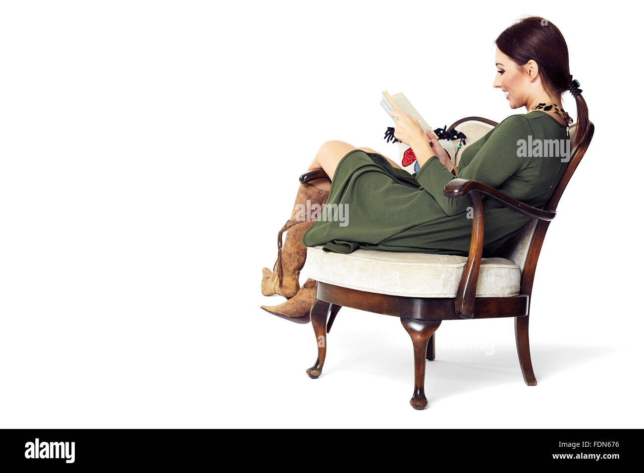 Cheerful woman sitting on chair and reading a book. Isolated on white background. Stock Photo